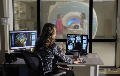 MRI tech sits in control room of MRI scanner